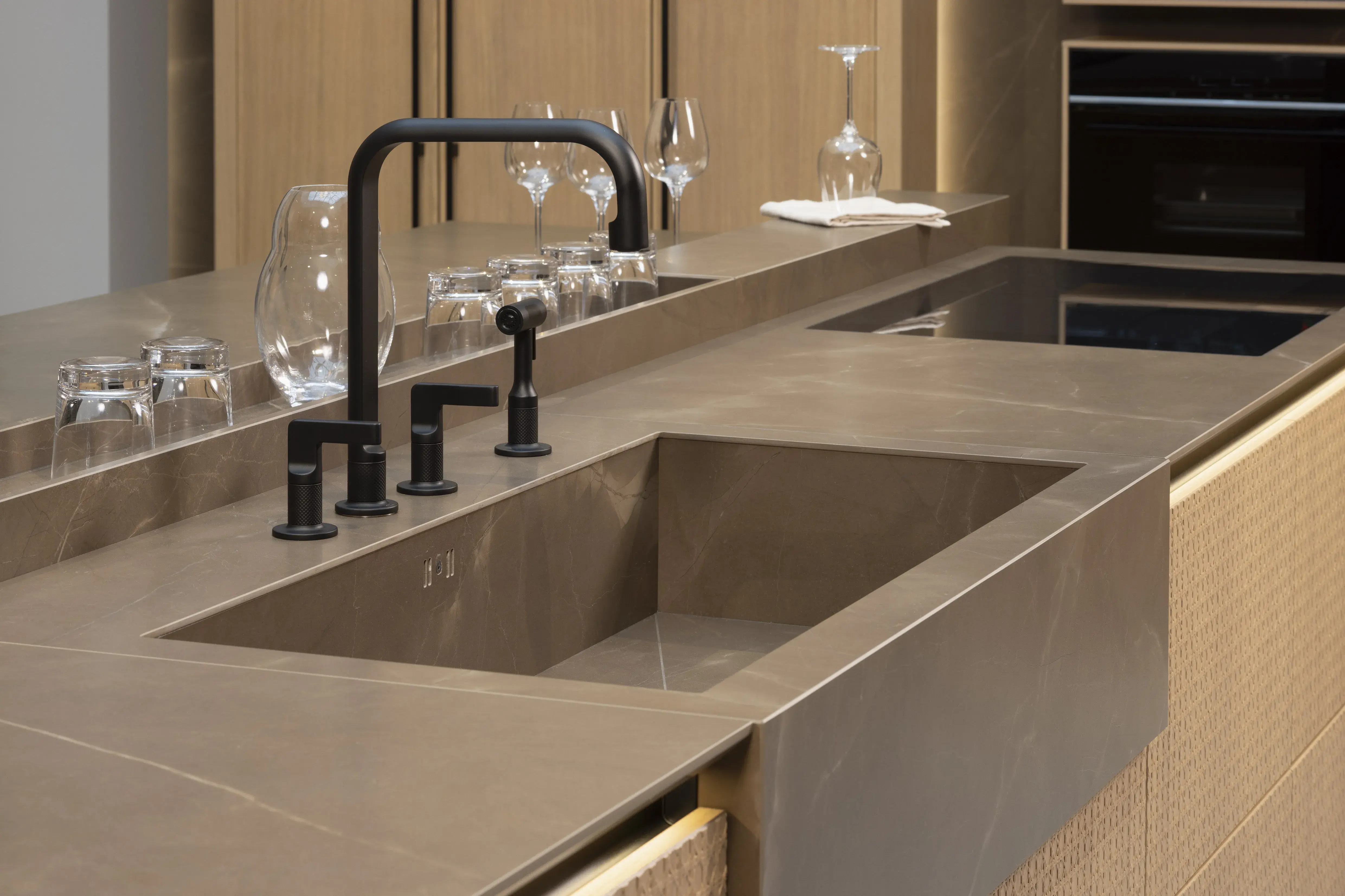 APL: Pulpis (Keramik) 25 mm Front: AV 6085-GL Eiche-elegant Echtholzfurnier (PURemission) Korpus: 2085 Designkorpus Feineiche-natur Griff: Kehlleiste 355 Schwarz matt Geräte: Siemens  Armatur: Gessi Spüle: ?  Features: neue Oberfläche Wiener Geflecht in Echtholzfurnier, Oberflächenmix, Waschbecken (Spülstein) in APL-Material, schwebende Arbeitsplatte durch Lichtleiste, APL abgekantet (schwebend), Backöfen in Wand eingekoffert, 3 Materialfarben.