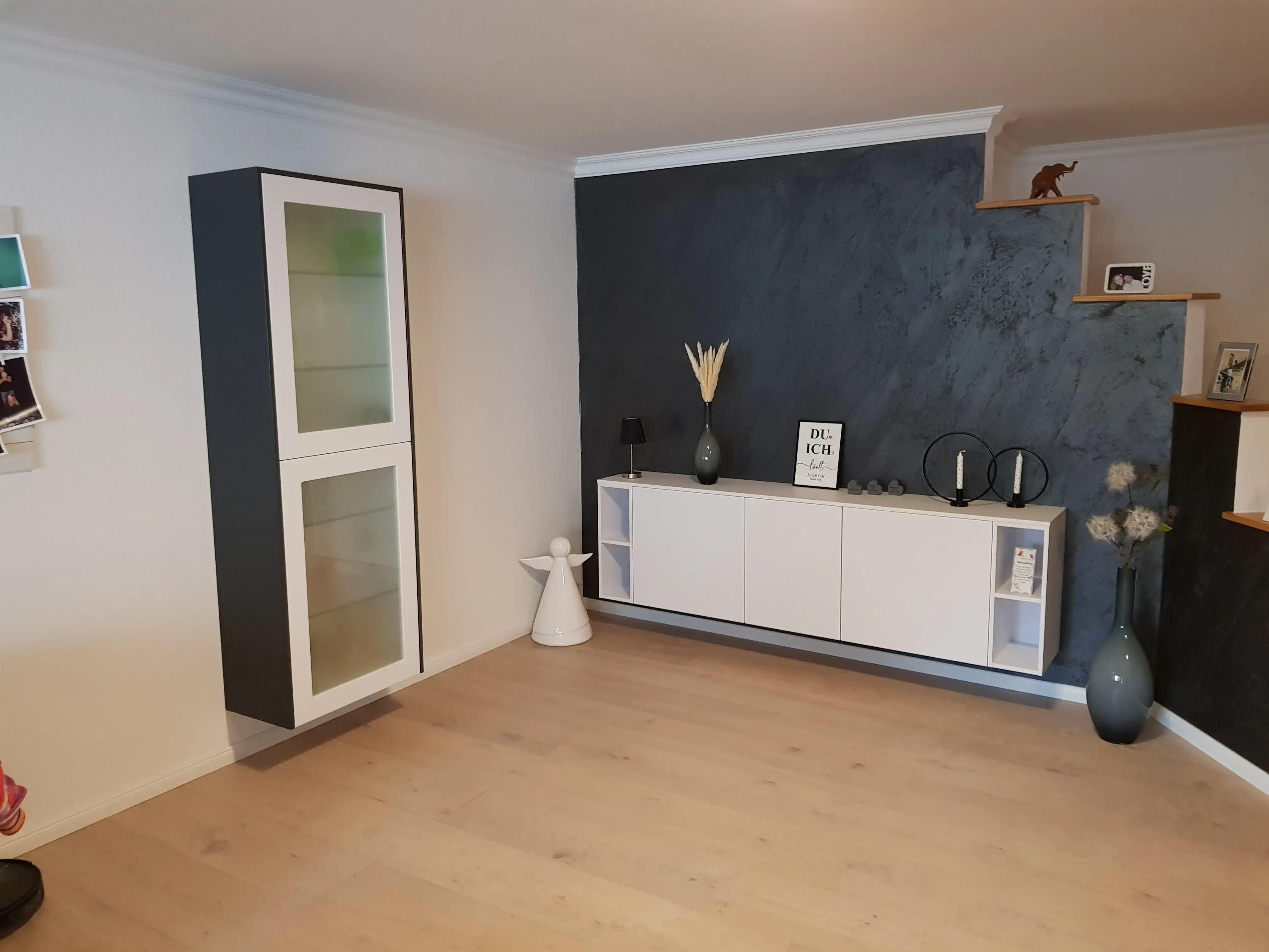 Modernes Wohnzimmer mit hängenden Schränken und dunkelgrauer Akzentwand.