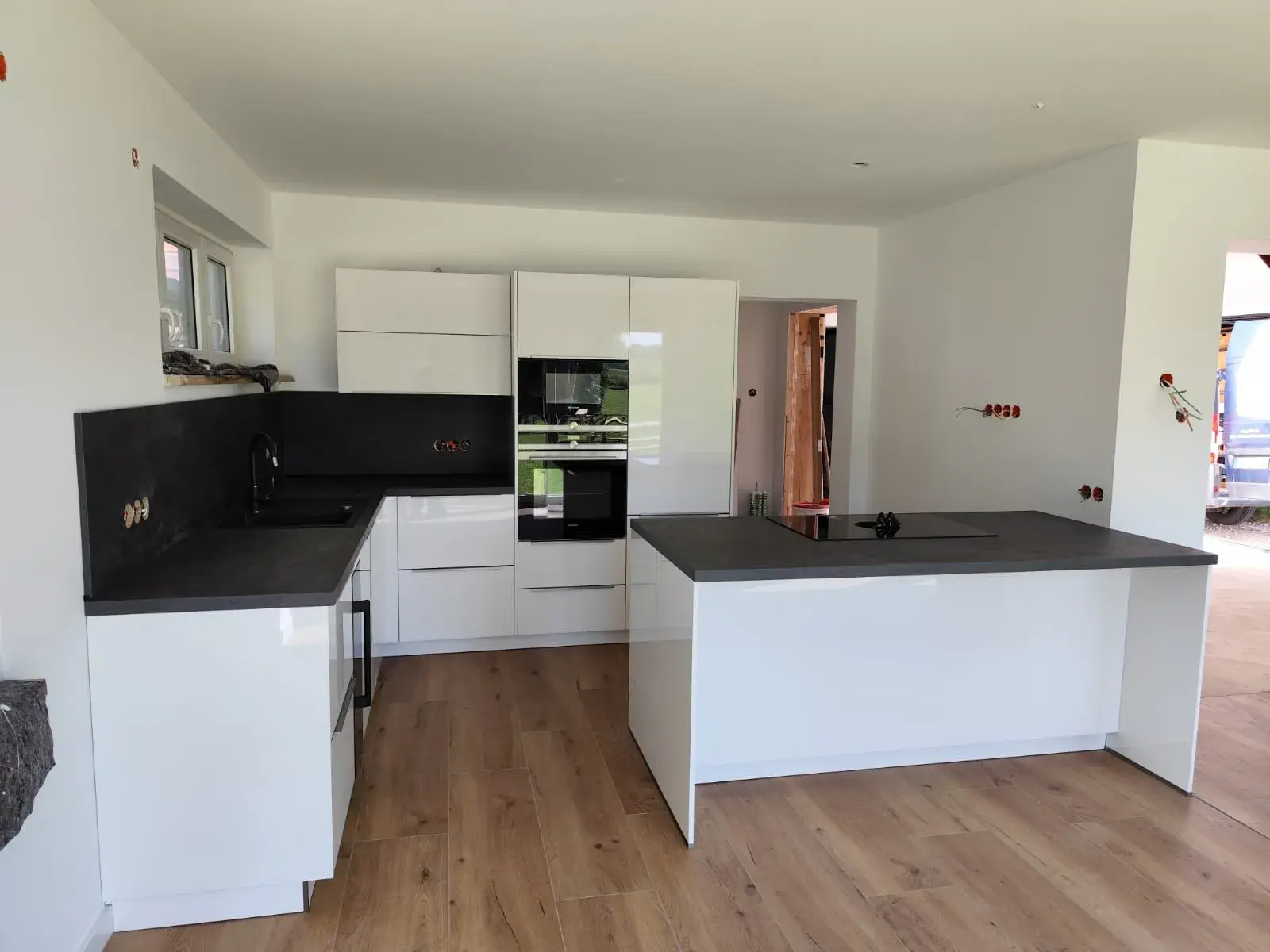 Moderne weiße Küche mit Kochinsel und Holzfußboden.