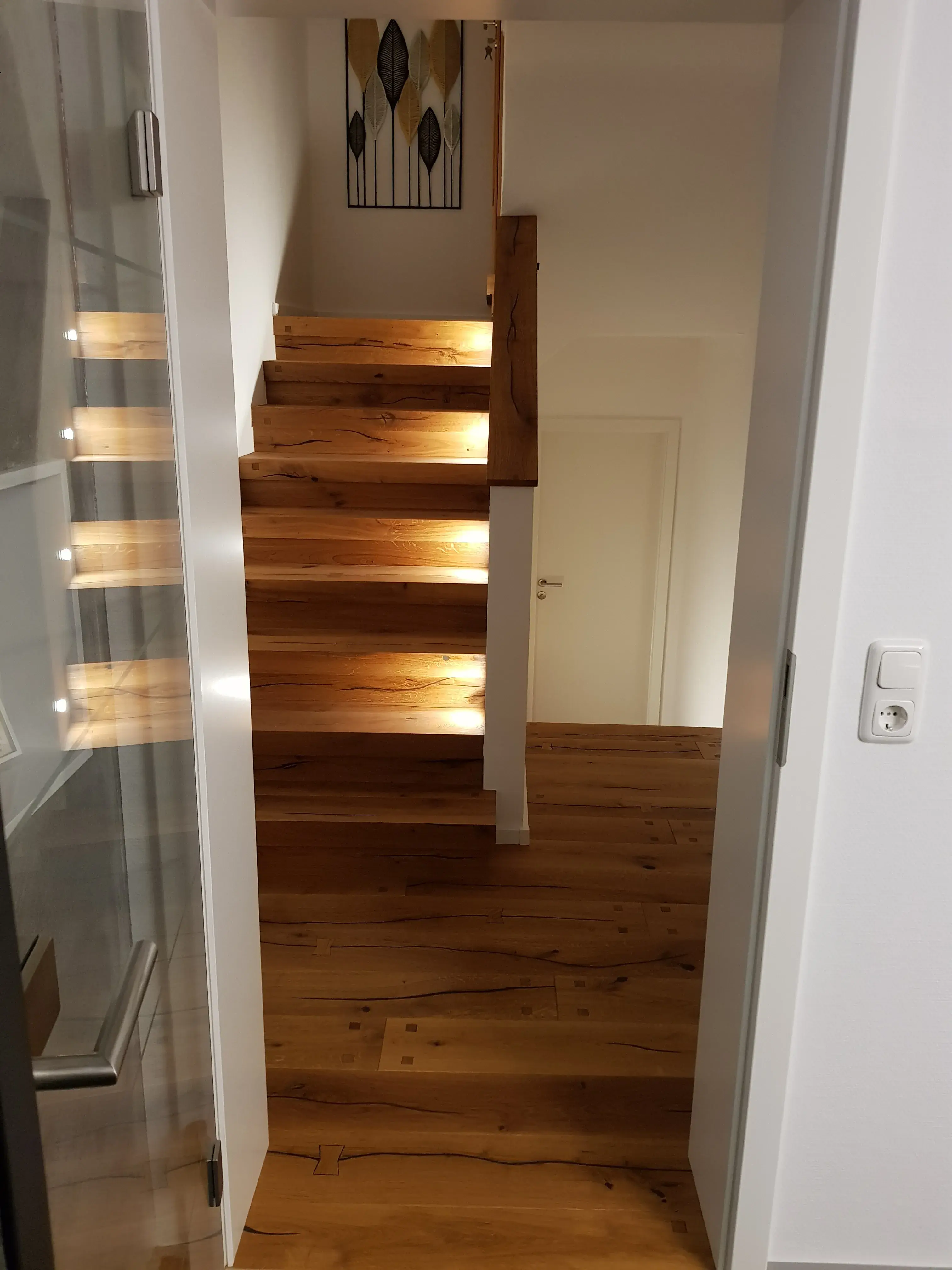 Holztreppe mit eingebauten LED-Leuchten in modernem Flur.