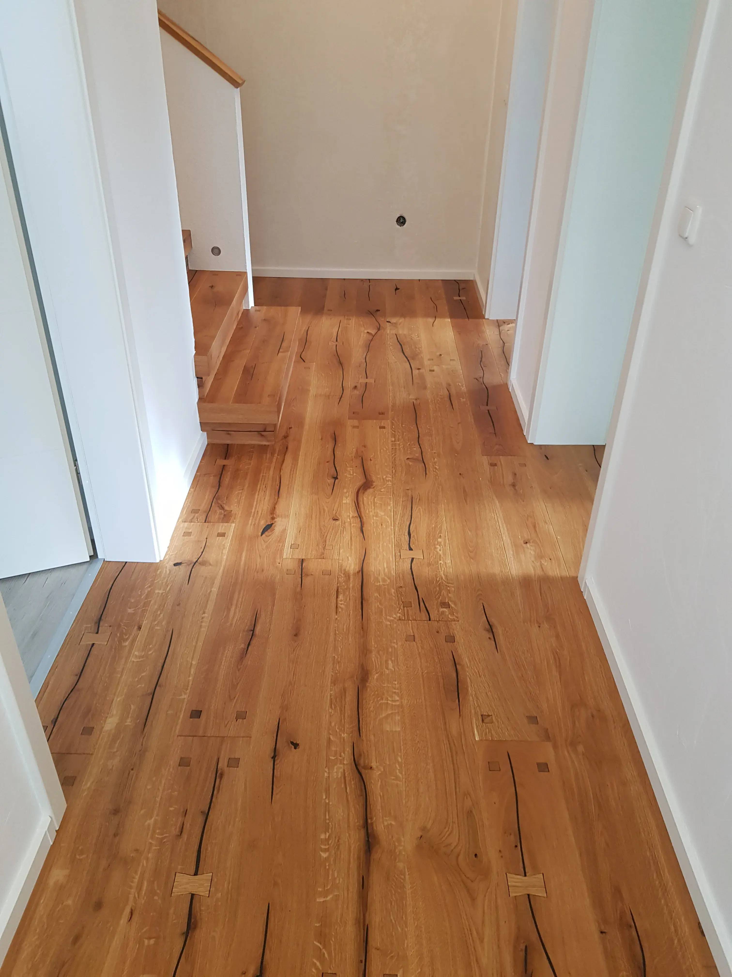 Flur mit hellen Wänden und neu verlegtem Holzfußboden